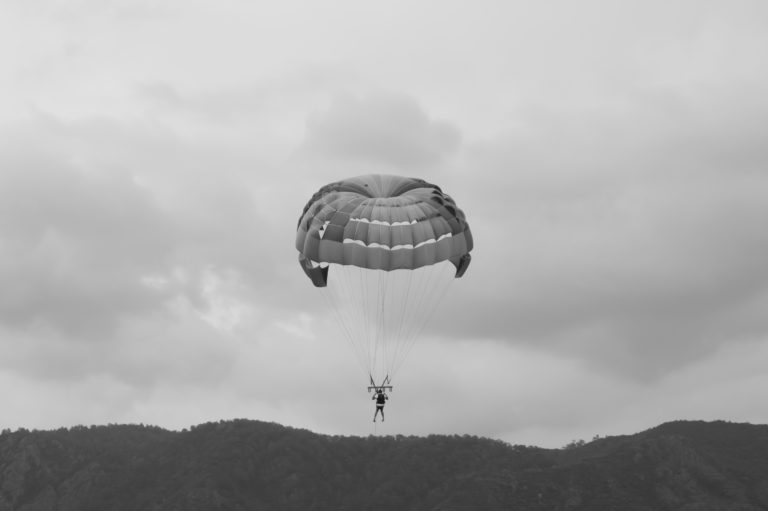 Skydiver flying with a parachute black and white background