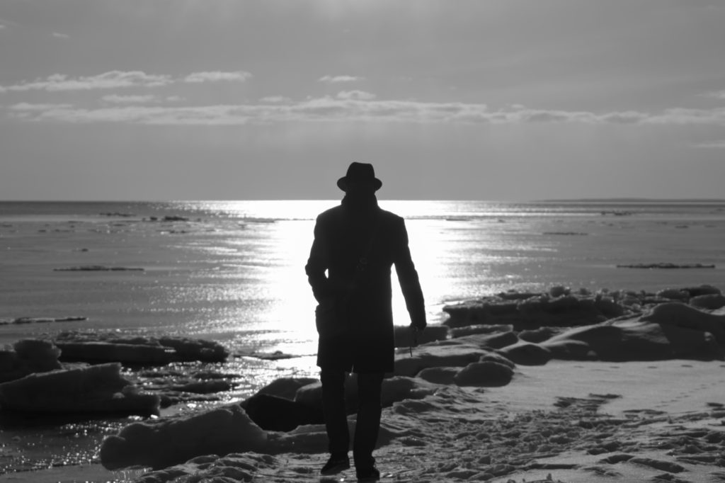 Lonely man walking on a beach black and white