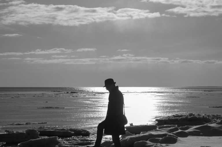 Lonely man walking on a beach black and white